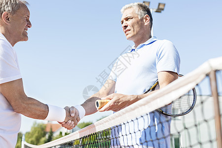 阳光明媚的日子里,男人们网球网前握手图片