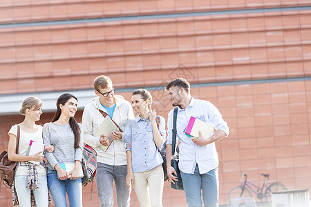 快乐的朋友大学校园里散步时书交谈图片