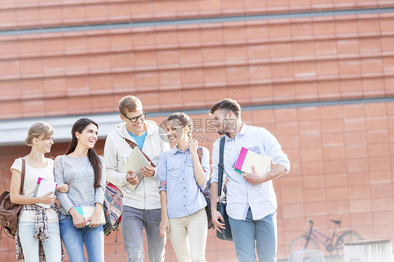 快乐的朋友大学校园里散步时书交谈图片