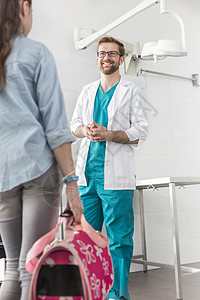 微笑的医生看着女孩站宠物载体兽医诊所图片