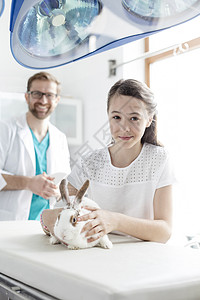 兽医诊所与医生床上兔子女孩的肖像图片
