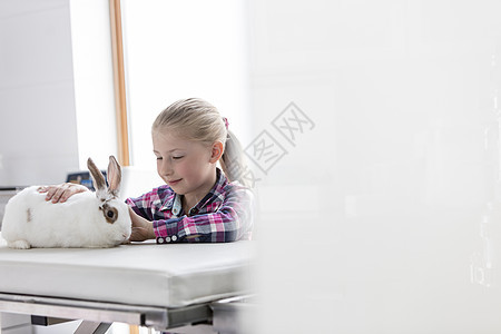 可爱的女孩兽医诊所床上看兔子图片