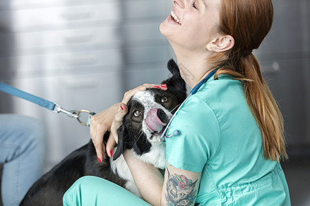 微笑的年轻兽医诊所拥抱狗图片