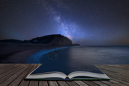令人震惊的充满活力的银河复合图像,多塞特西湾长时间曝光的景观上,魔法故事书的页面中出来图片