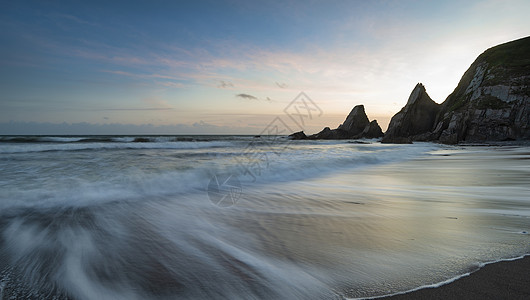 美丽的日落景观图像韦斯特康贝海滩德文英格兰与锯齿状的岩石海滩惊人的云背景图片