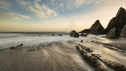 海滩岩石日落美丽的日落景观图像韦斯特康贝海滩德文英格兰与锯齿状的岩石海滩惊人的云背景