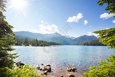 平静的景色加大的山湖旁边,岩石平静的水中反射图片