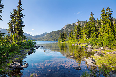 平静的景色加大的山湖旁边,岩石平静的水中反射图片