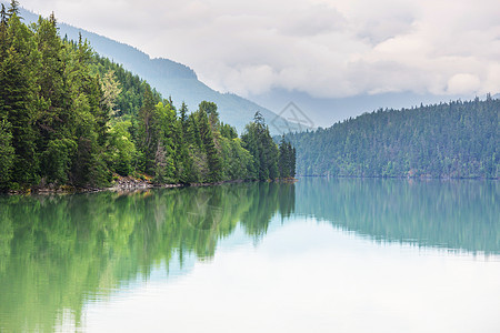 平静的景色加大的山湖旁边,岩石平静的水中反射图片