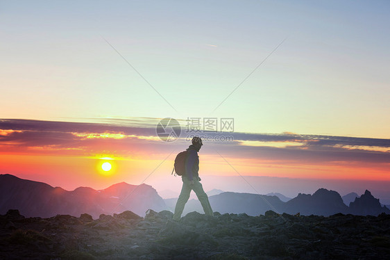 日落时美丽的夏季山脉中的徒步旅行场景图片