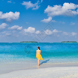 穿着连衣裙的女人热带海滩散步图片