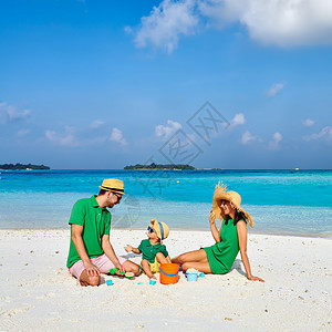 海滩上的家人,穿着绿色衣服的轻夫妇三岁的男孩马尔代夫的暑假图片