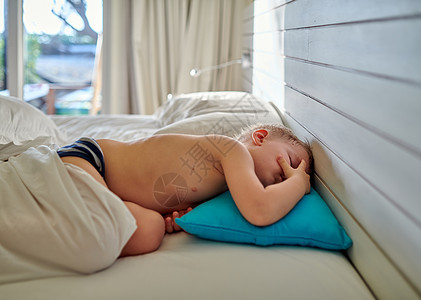 三岁的蹒跚学步的男孩睡毯子下的蓝色枕头上图片