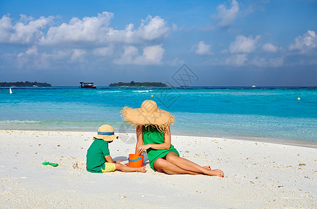 海滩上的家人,穿着绿色连衣裙的女人三岁的男孩马尔代夫的暑假图片