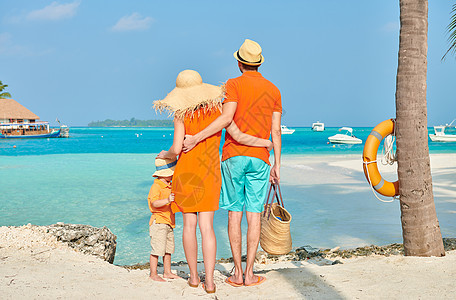 家人海滩上,穿着橙色衣服的轻夫妇三岁的男孩棕榈树下马尔代夫的暑假图片