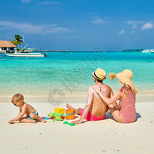 海滩上的家人,三岁男孩的轻夫妇女男背部涂防晒霜马尔代夫的暑假图片