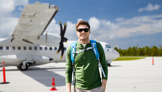 旅行,旅游人的微笑的轻人戴着太阳镜,背包飞机上的机场背景带着背包机场飞机上微笑的人图片