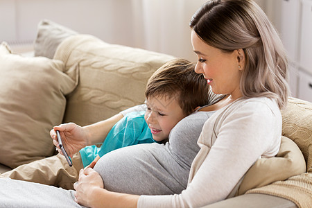 家庭,技术怀孕快乐的怀孕母亲小儿子与智能手机家里怀孕的母子智能手机家图片