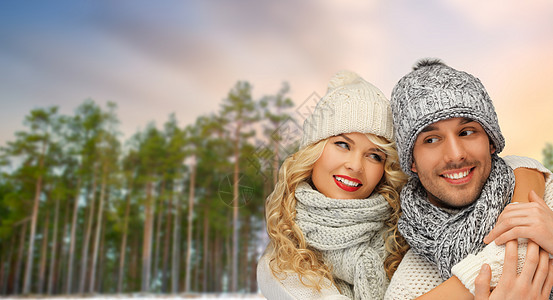 冬天,诞节人们的幸福的戴着帽子围巾拥抱森林背景上夫妇拥抱冬天的森林背景上图片