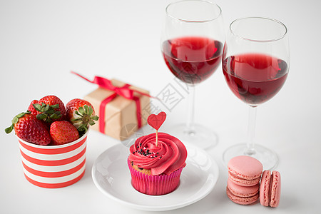 情人节糖果磨砂纸杯蛋糕与红色心形鸡尾酒棒,马卡龙,草莓,酒杯礼品盒白色背景情人节的红色糖果图片