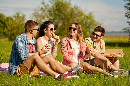 友谊休闲食物群微笑的朋友夏季公园野餐时吃比萨饼朋友们夏天公园野餐时吃比萨饼图片