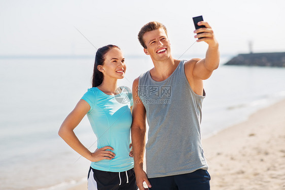 健身,运动生活方式的快乐的夫妇穿着运动服,海滩上用智能手机自拍夫妇海滩上用智能手机自拍图片