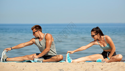 健身,运动生活方式的快乐的夫妇伸展腿海滩上训练前快乐的夫妇海滩上伸展腿图片