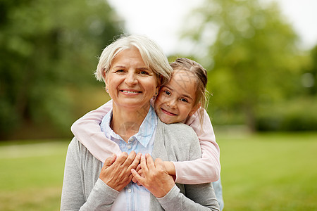 家庭,休闲人的快乐的孙女拥抱她的祖母夏季公园孙女夏天公园拥抱祖母图片