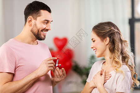 爱,夫妇,求婚人的快乐的男人小红盒子里给家里的女人钻石订婚戒指男人情人节给女人订婚戒指背景图片