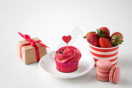 情人节糖果磨砂纸杯蛋糕与红色心形鸡尾酒棒,马卡龙,草莓礼品盒白色背景情人节的红色糖果图片