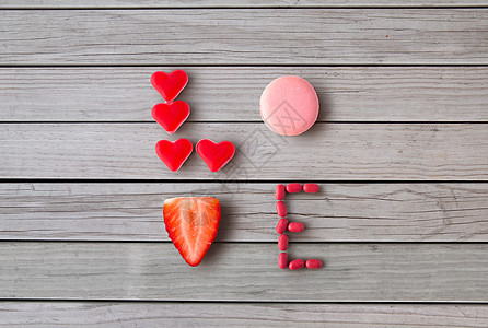 情人节,糖果糖果的文字爱由红色心形糖果,粉红色通心粉饼干草莓灰色木板背景用糖果的爱图片