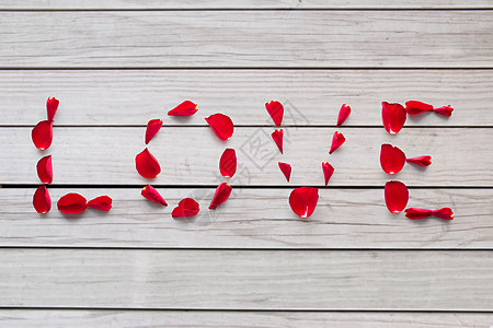 情人节浪漫的文字爱情由红色玫瑰花瓣制成的灰色木板背景用红玫瑰花瓣的爱图片