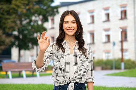 教育,学校人的微笑的轻妇女十几岁的女孩穿着格子衬衫,校园背景上OK手签十几岁的女孩校园里展示OK手签名图片