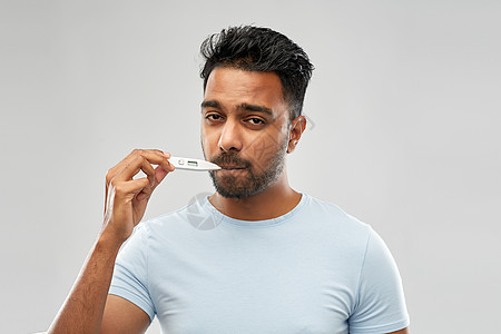 人,医疗保健发烧健康的印度男子测量口腔温度的温度计灰色背景用温度计测量口腔温度的人图片
