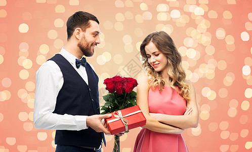 互送礼物情侣情人节,情侣,关系人的快乐的男人给女人鲜花,并呈现活生生的珊瑚背景节日灯快乐的男人给女人鲜花礼物背景