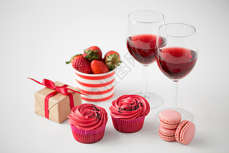 情人节糖果糖霜纸杯蛋糕,马卡龙,草莓,红酒杯礼品盒白色背景情人节的红色糖果图片
