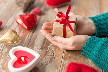 诞节,情人节假日女手礼品盒与心形装饰蜡烛燃烧木制背景紧握着诞礼物的手背景图片