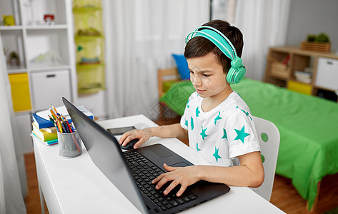 技术,游戏人的男孩耳机玩电子游戏笔记本电脑家里戴耳机的男孩笔记本电脑上玩电子游戏图片