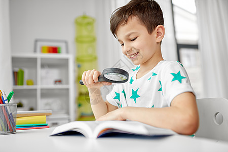 童,教育好奇心的快乐的小男孩与放大镜阅读探索书家里带放大镜家看书的男孩图片