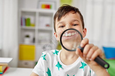 童,趣好奇的快乐的小男孩与放大镜大牙齿家里带放大镜的男孩家里露出大牙图片