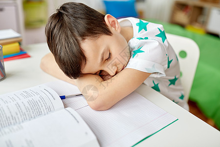 教育,童学校的疲惫的学生男孩睡家里的桌子上疲惫的学生男孩睡家里的桌子上背景图片