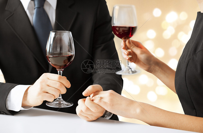 ‘~庆祝,订婚人的亲密的订婚夫妇喝红酒,牵手米色背景与节日灯亲密的订婚夫妇喝红酒  ~’ 的图片