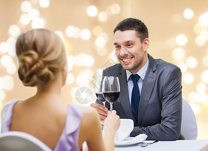 约会,庆祝情人节的微笑的轻夫妇碰杯含酒精的红酒,并餐厅的节日灯米色背景轻的夫妇餐厅喝了杯酒图片