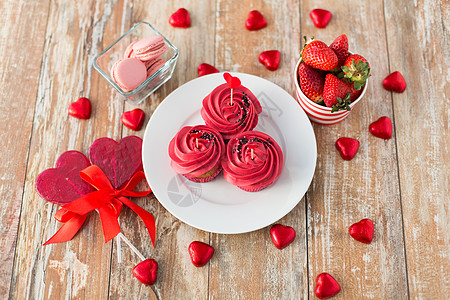 草莓糖霜蛋糕情人节糖果糖霜纸杯蛋糕,红色心形巧克力糖果,棒棒糖,马卡龙草莓为情人节红色糖果背景