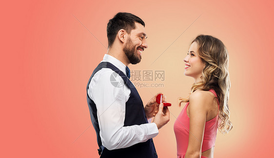 爱情,夫妻,求婚人的快乐的男人小红盒子里给生活珊瑚背景下的女人钻石订婚戒指男人情人节给女人订婚戒指图片