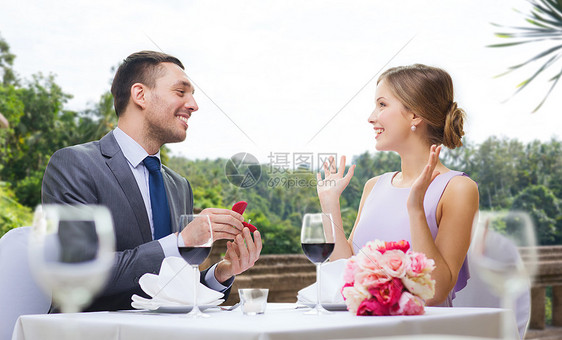 求婚,情人节人们的兴奋的轻女人看着男朋友给她的订婚戒指餐厅的夏季背景餐馆给女人订婚戒指的男人图片