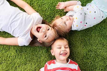 童,休闲家庭观念快乐的孩子躺地板地毯上快乐的小孩子躺地板地毯上图片