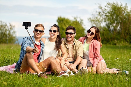 友谊休闲技术群快乐的微笑朋友夏天的户外自拍杆上用智能手机拍照朋友们夏天用自拍杆拍照图片
