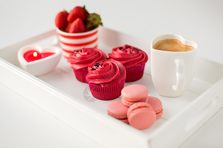 情人节糖果纸杯蛋糕与红色奶油霜,马卡龙,心形咖啡杯,蜡烛草莓托盘情人节的红色糖果图片
