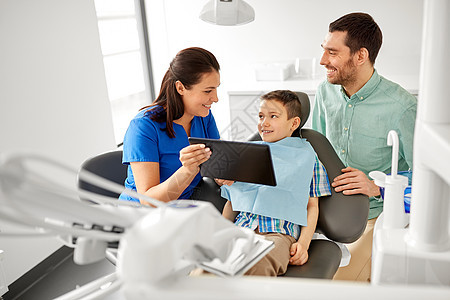 医学,牙科医疗保健牙医向儿童病人他的父亲牙科诊所展示平板电脑牙医牙科诊所向孩子展示平板电脑图片